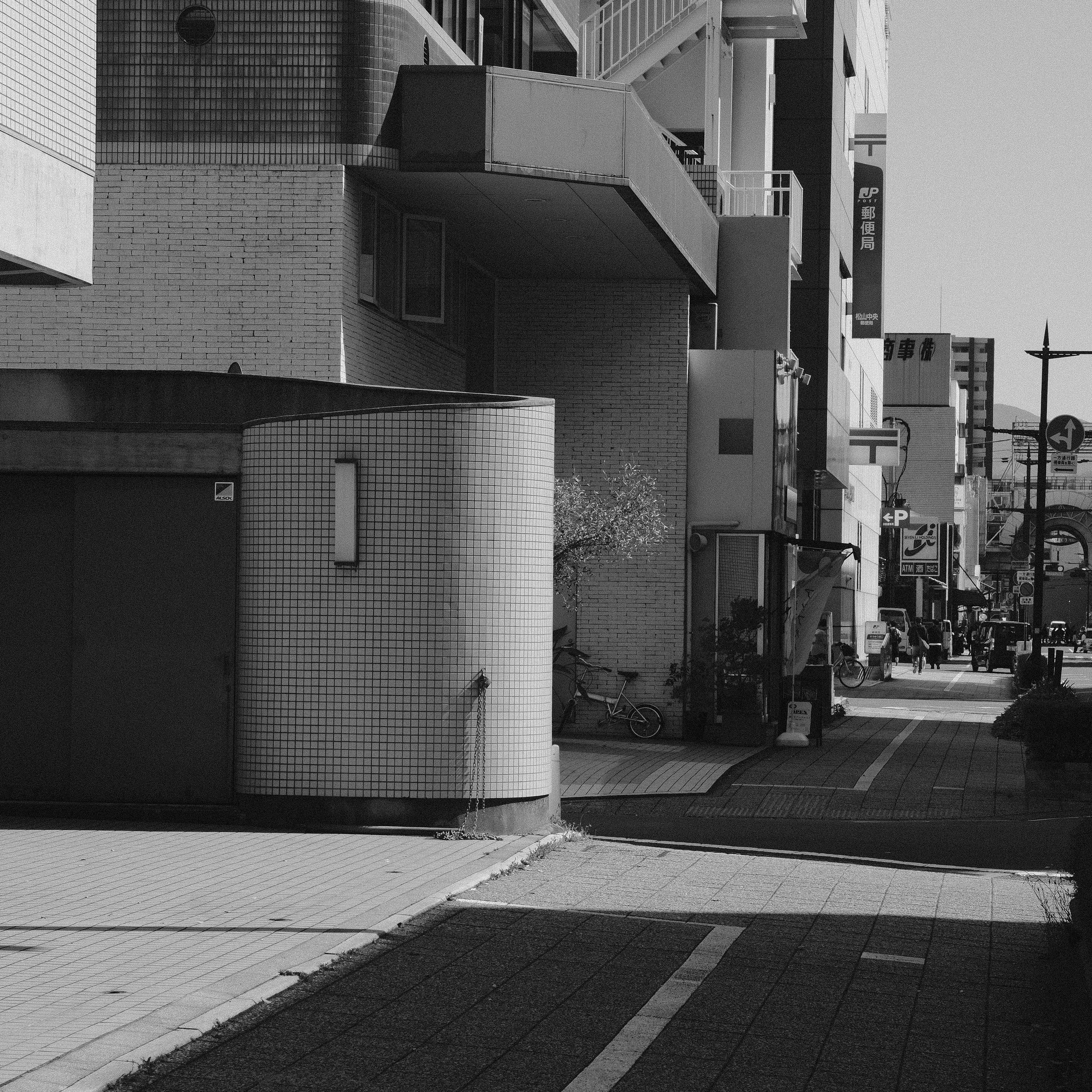 A black and white photo capturing an urban street scene with modern architecture.