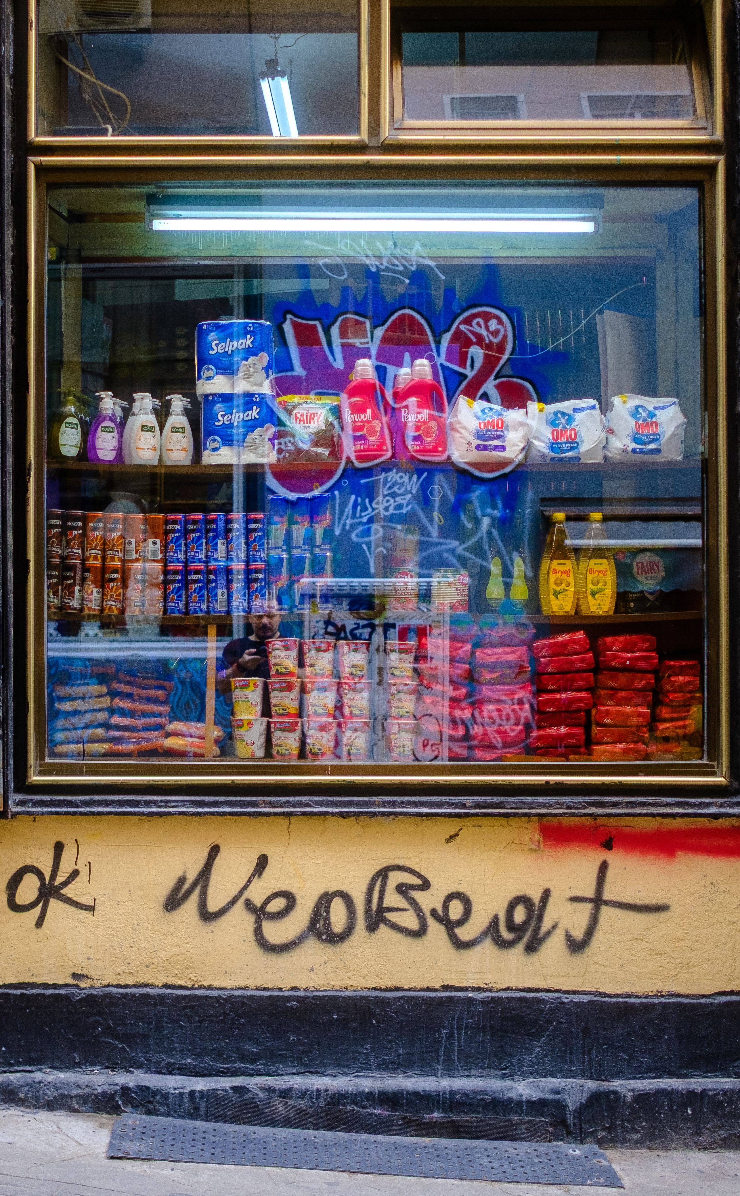 Vibrant storefront window showcasing grocery items with graffiti art.