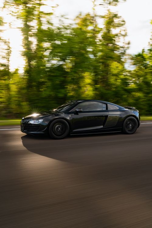 Free Dynamic motion shot of a luxury black sports car driving on a scenic road. Stock Photo