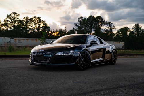 Free Stunning black sports car parked outdoors with a sunset backdrop, showcasing luxury and style. Stock Photo