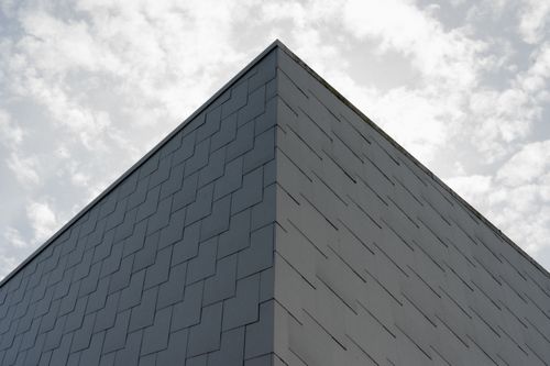 Free A minimalist corner view of a modern building in Porsgrunn, Norway, against a cloudy sky. Stock Photo