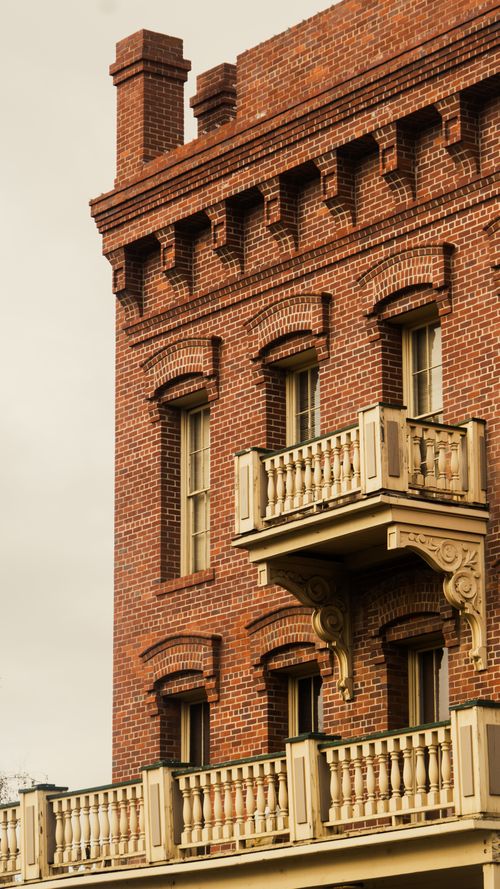 Free Close-up of a classic brick building facade with ornate balconies and detailed architecture. Stock Photo