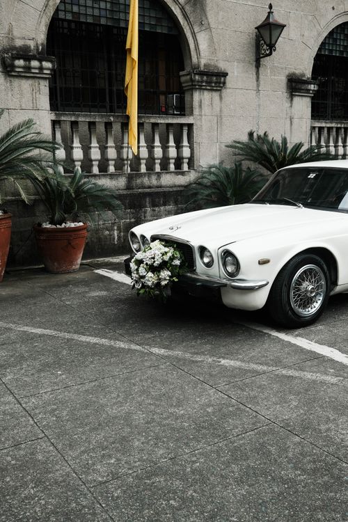Free A vintage white car adorned with flowers parked in historic Intramuros, Manila, Philippines. Stock Photo
