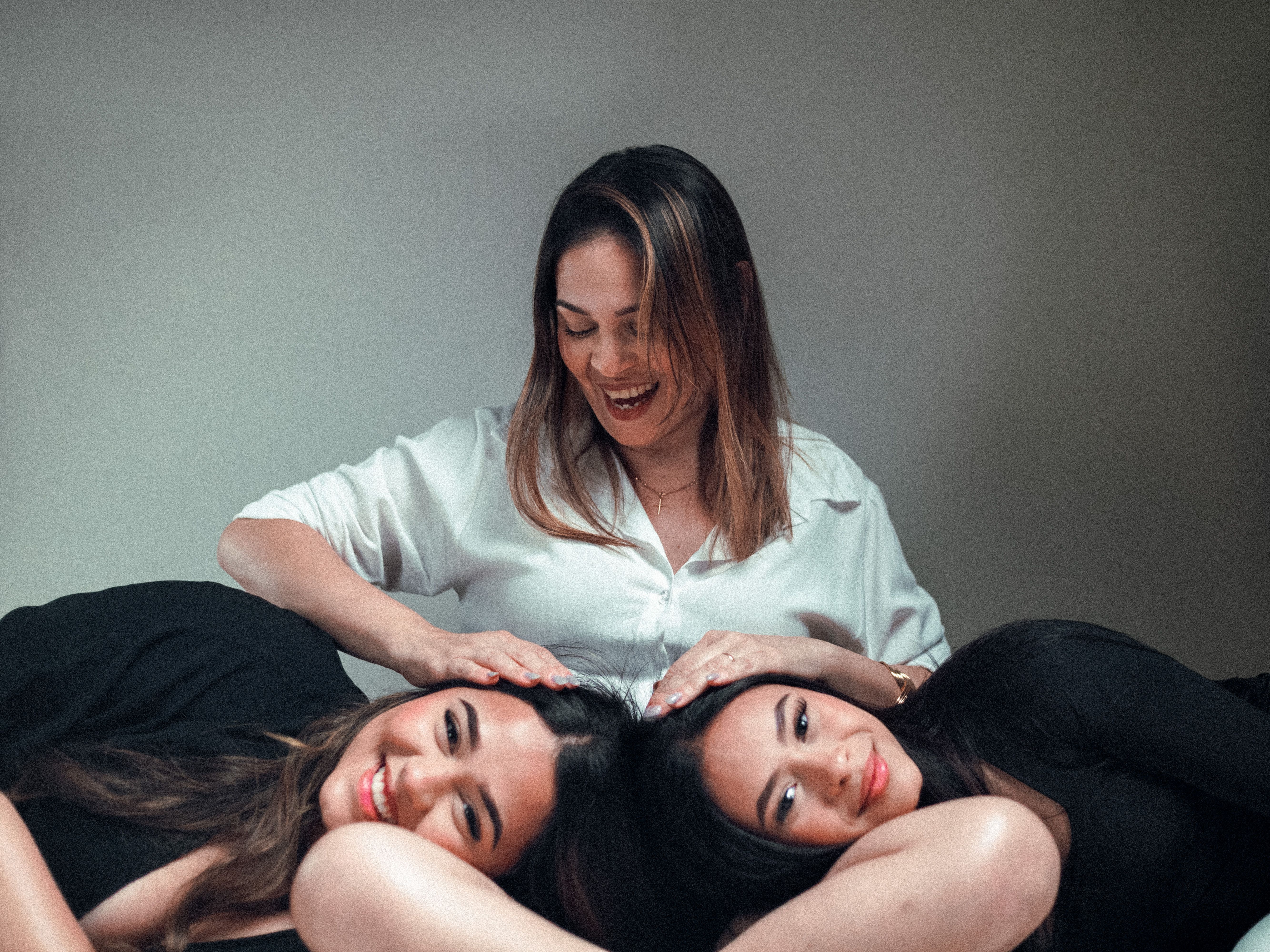 Three women enjoying a joyful moment together, displaying affection and happiness indoors.
