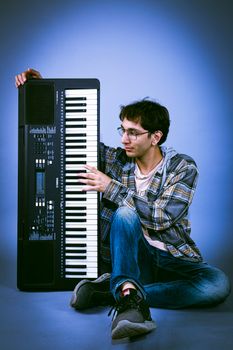 Young musician with keyboard in a relaxed pose. Modern and creative vibe.