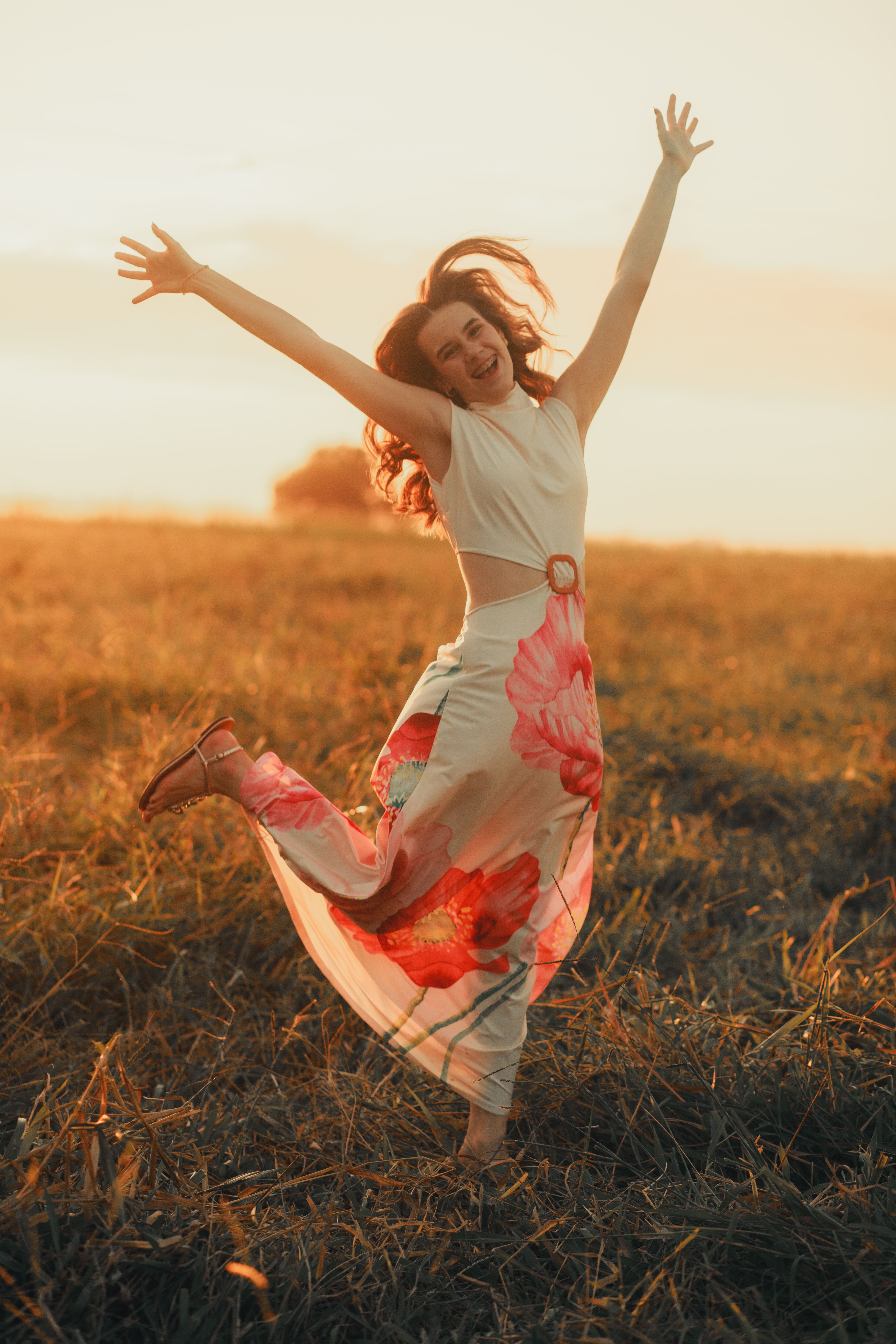 Joyful Woman in Sunlit Field at Sunset · Free Stock Photo
