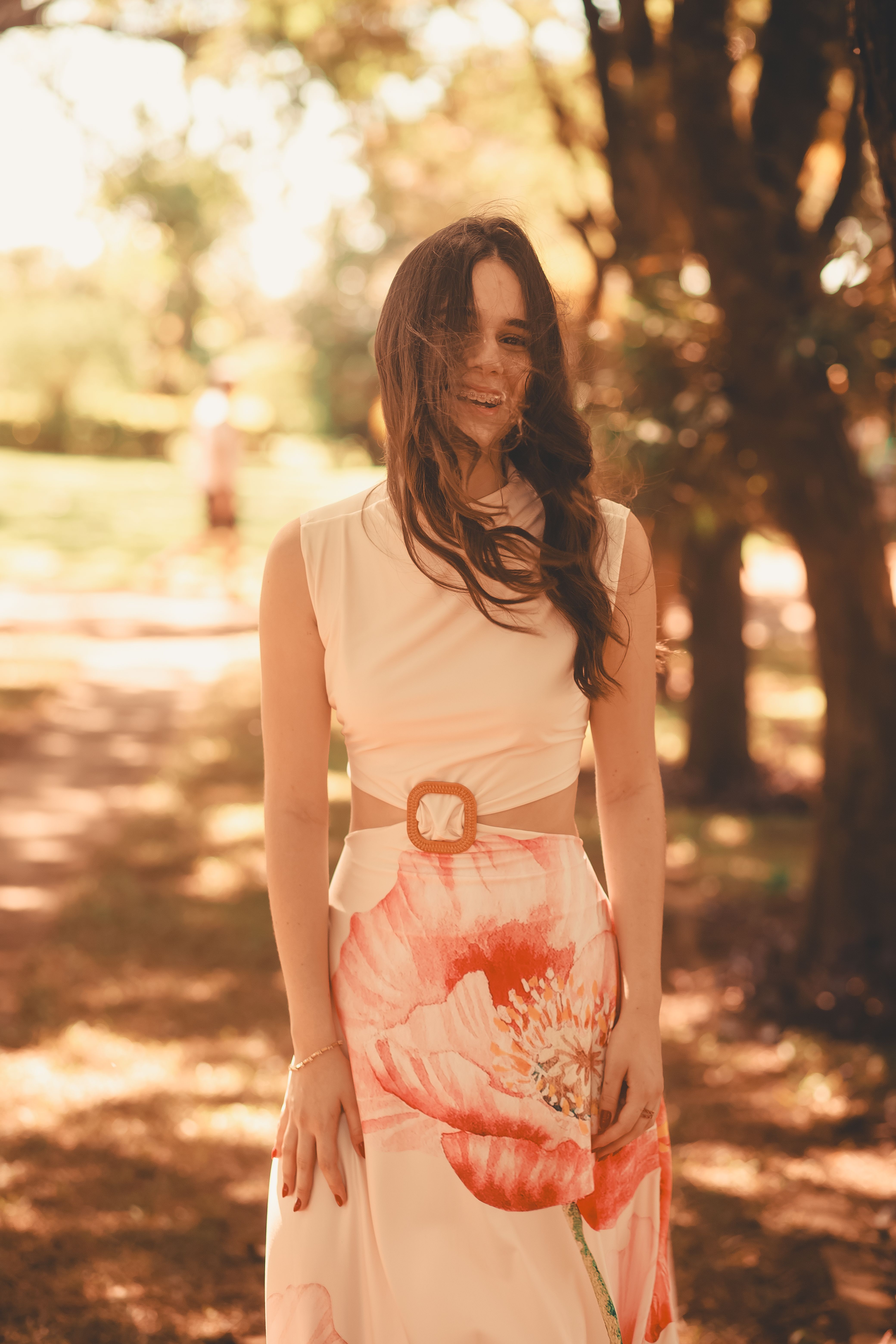 Elegant Woman in Sunlit Park Wearing Floral Dress · Free Stock Photo