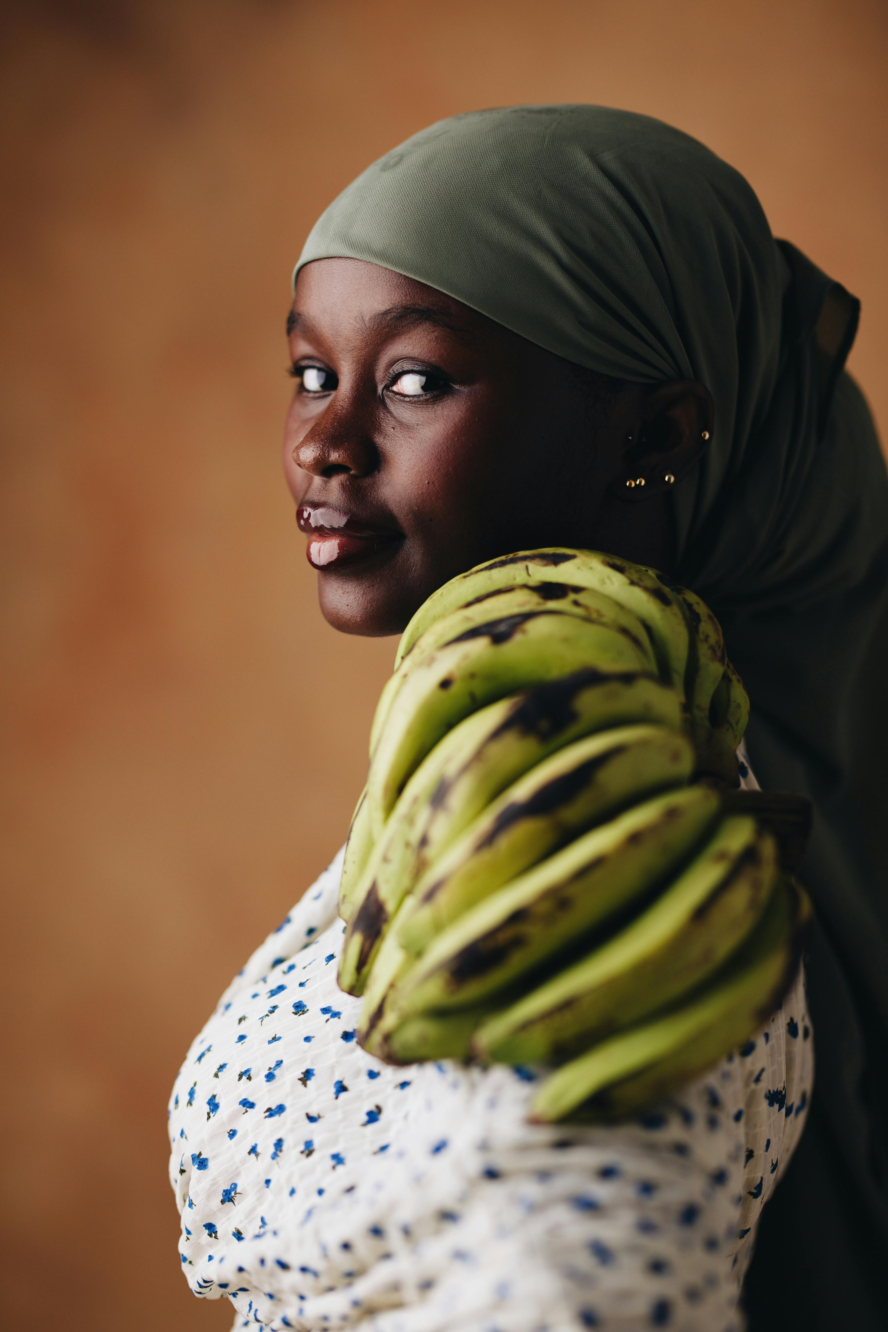 Elegant portrait of a woman carrying a bunch of bananas on her shoulder, creating a vibrant and natural feel.