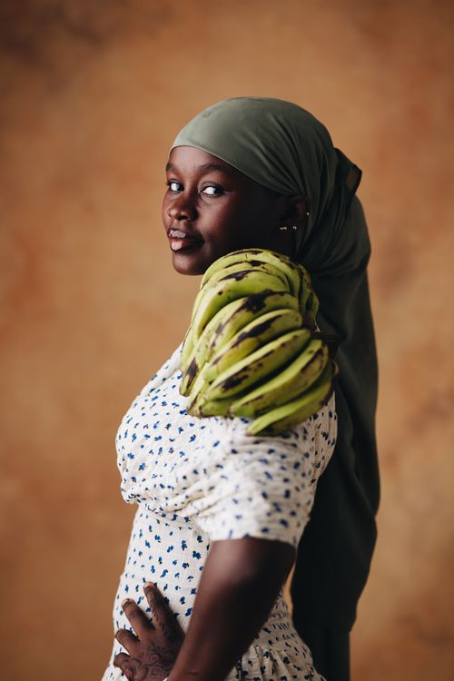 Free Elegant portrait of a woman in headscarf with fresh bananas on shoulder. Stock Photo