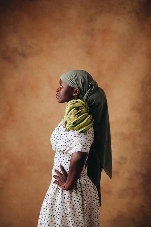 Free Elegant profile portrait of a woman in traditional attire holding bananas over a textured background. Stock Photo