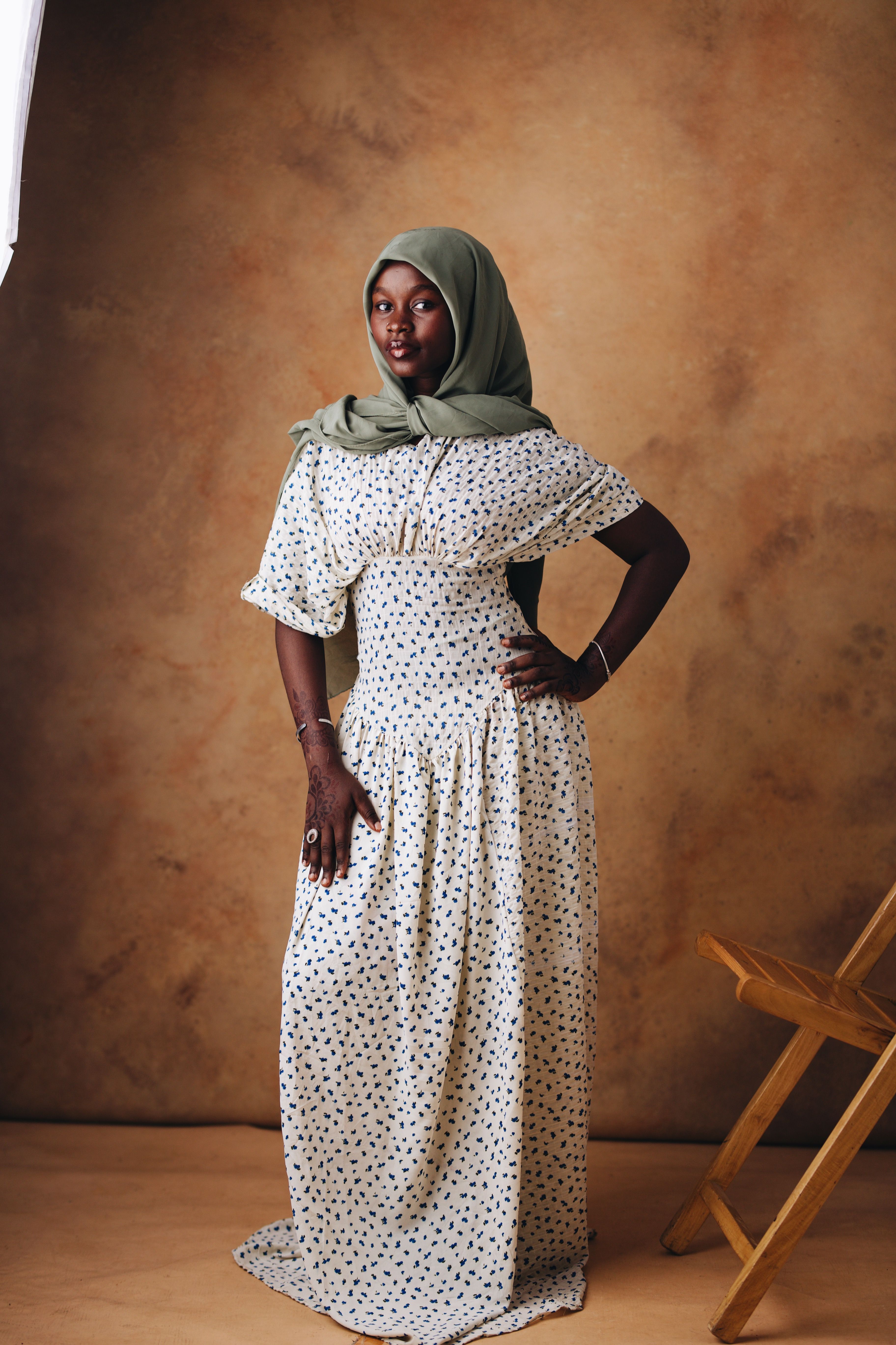 Sophisticated portrait of a woman wearing a green hijab and floral dress, exuding elegance.