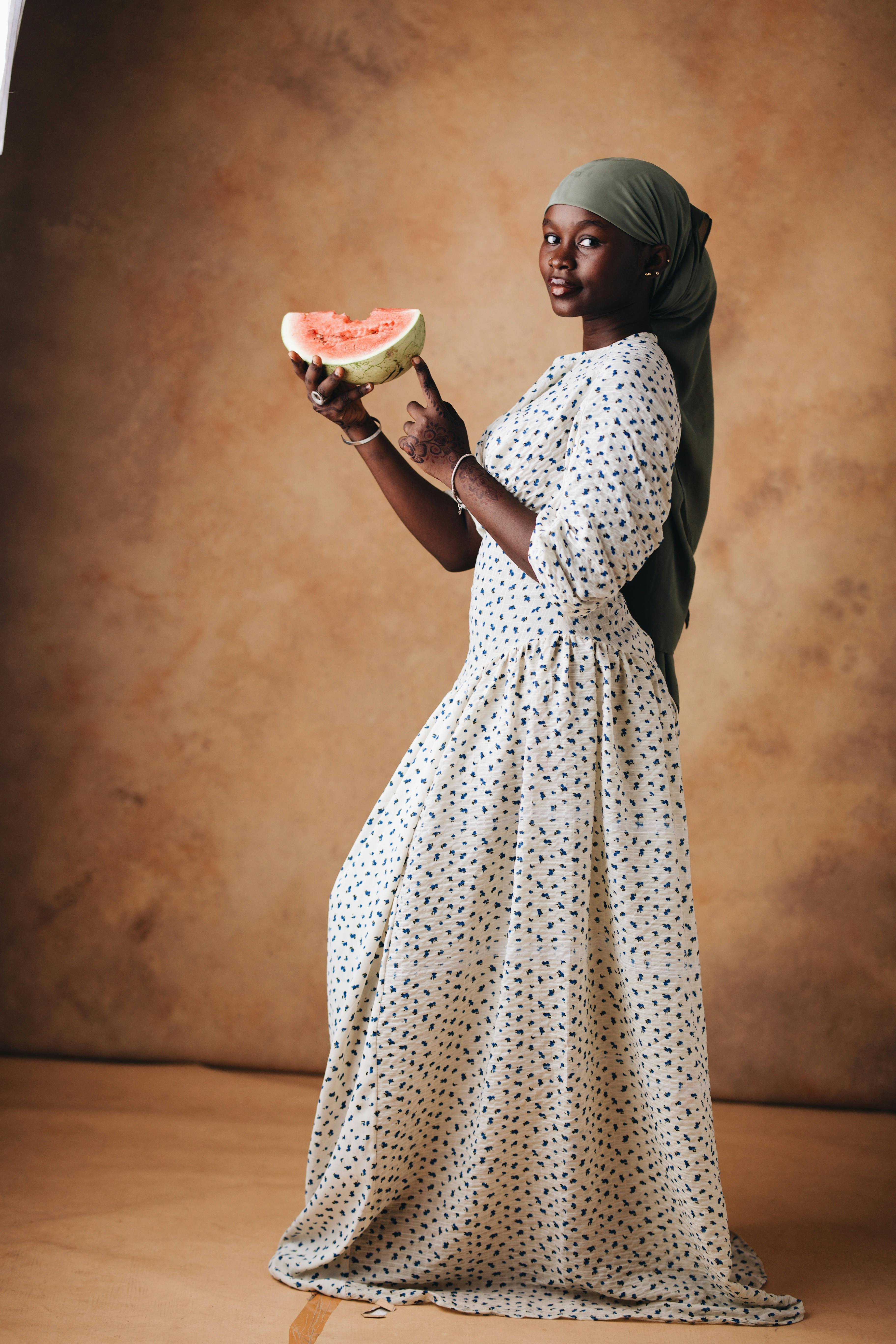 Portrait of an elegant woman in a long dress holding a watermelon slice, exuding a classic and artistic vibe.