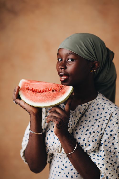 Free A young woman playfully holding a slice of watermelon indoors. Stock Photo