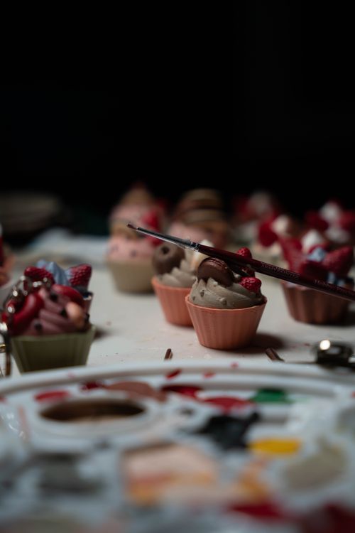 Free Captivating still life of miniature cupcakes with a paintbrush, showcasing a fusion of art and culinary delight. Stock Photo
