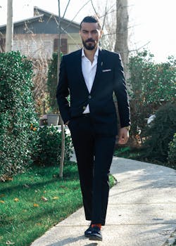 一位穿着正式服装的时尚商人，白天自信地走在花园小径上