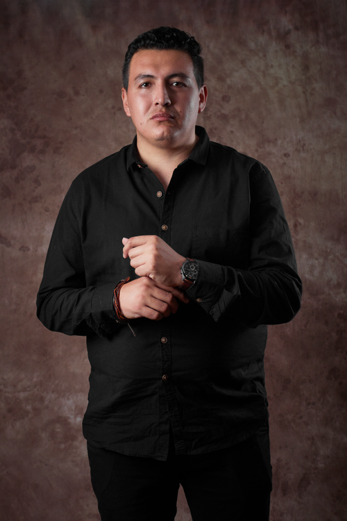 Free A confident young man poses in a black shirt against a textured brown background. Stock Photo
