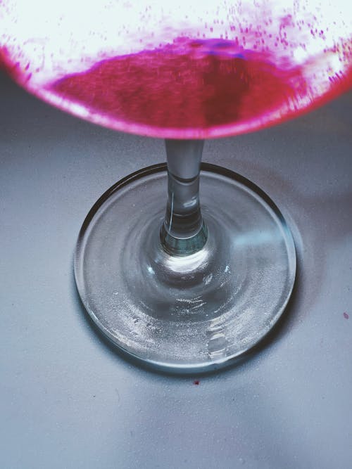 From above closeup of shiny wineglass with alcohol drink placed on white table