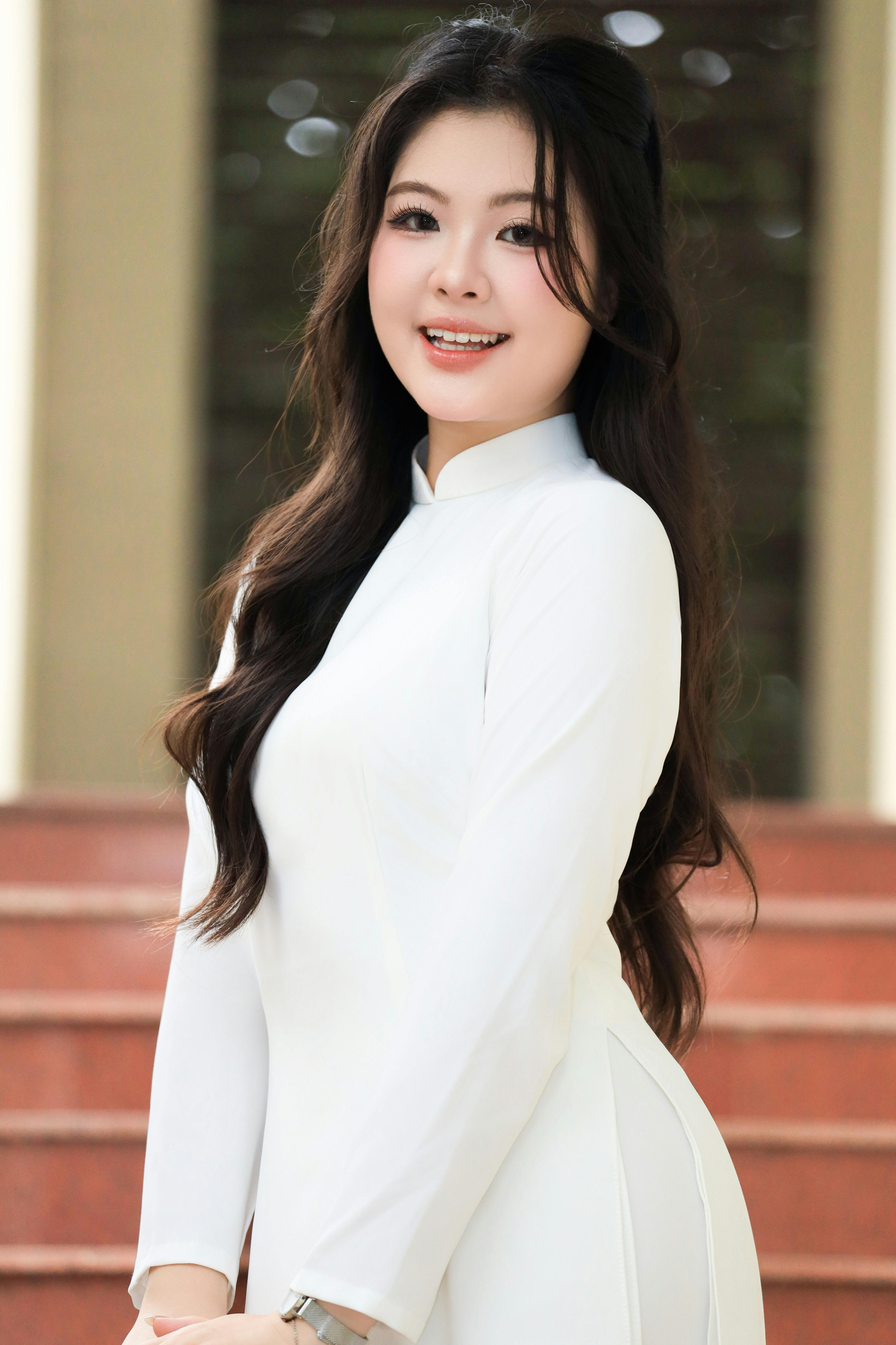Portrait of a young woman in a white Ao Dai standing on stairs in Vietnam.