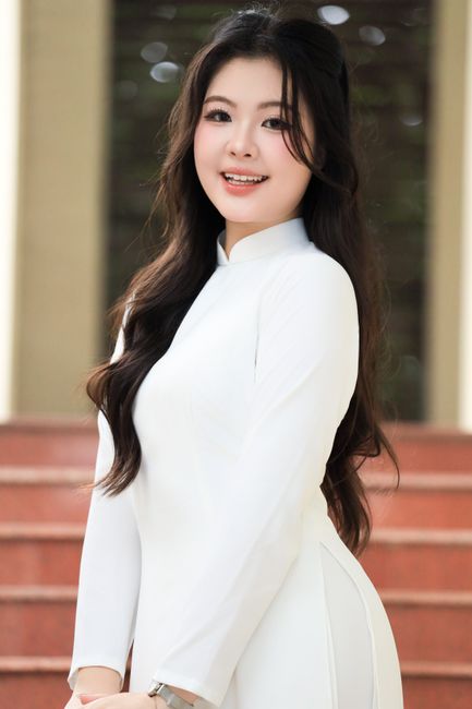 Portrait of a young woman in a white Ao Dai standing on stairs in Vietnam.