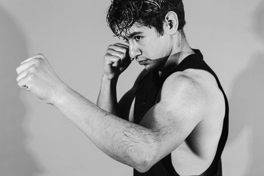 Monochrome portrait of a young male boxer in fighting stance, exuding focus and strength.