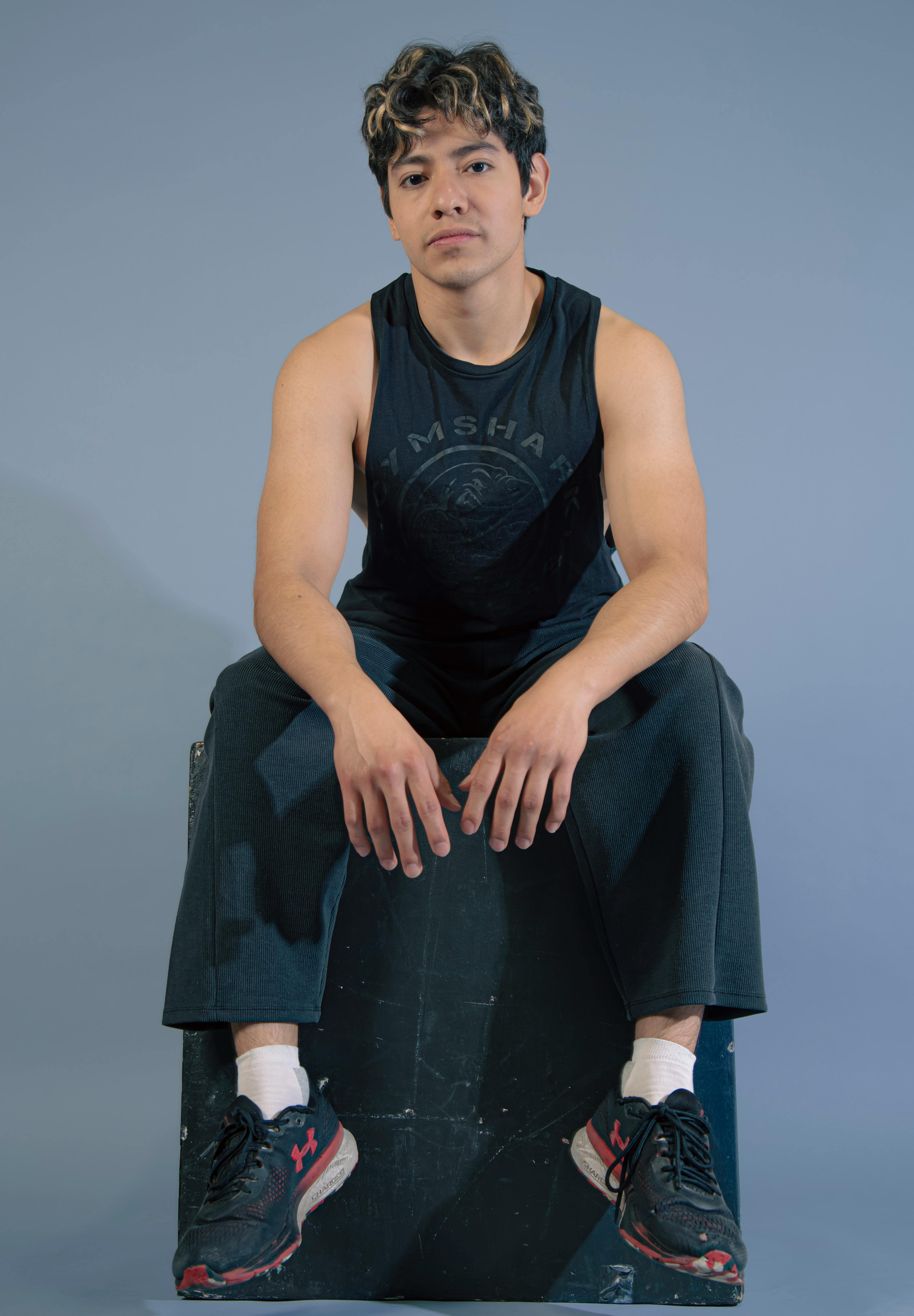 Portrait of a young man sitting indoors in casual athletic wear.