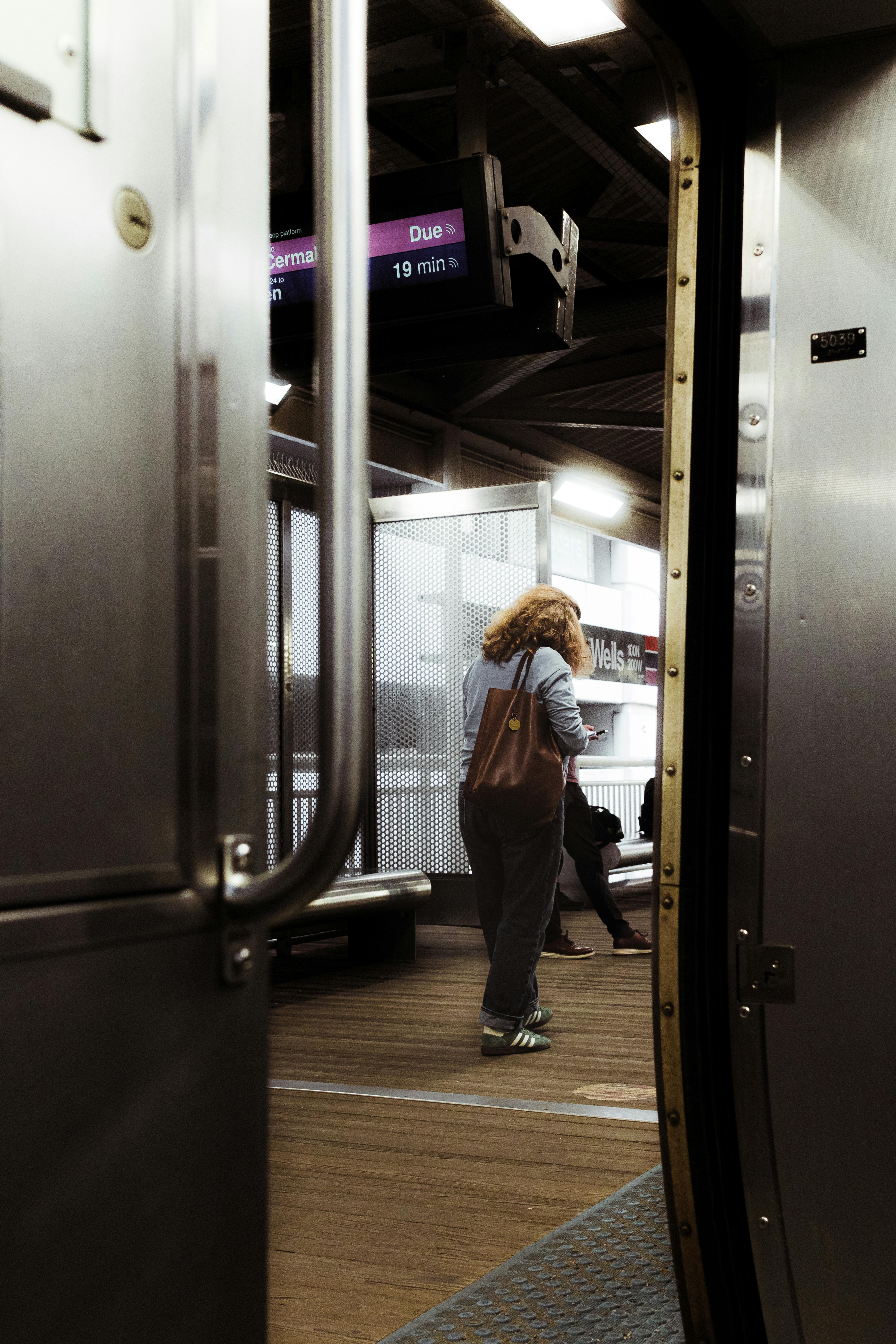 A candid shot of a person waiting at a Chicago subway station, with the platform and train door visible.
