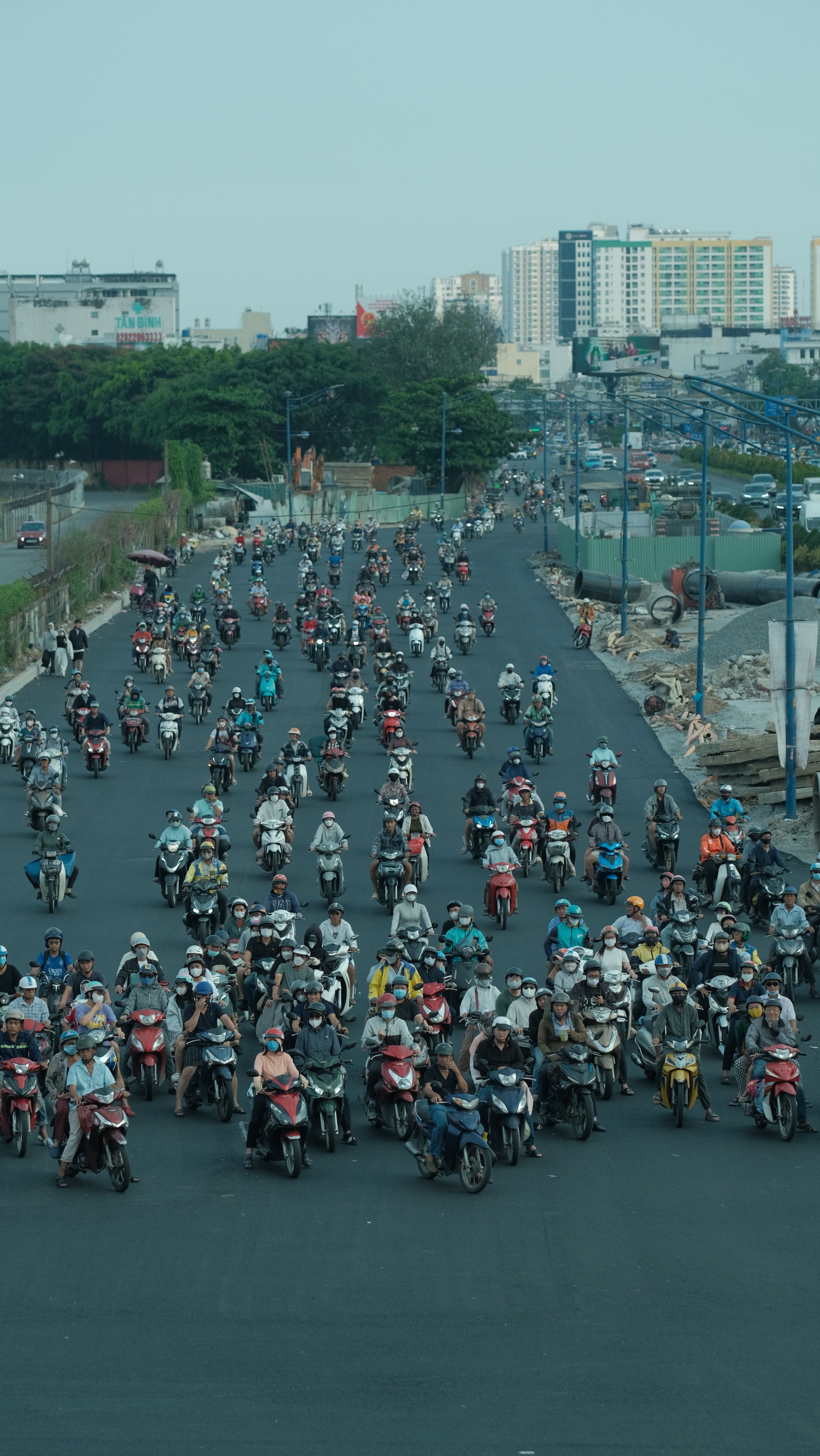 A busy street scene with many motorbike riders commuting in an urban area.