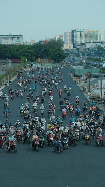 A busy street scene with many motorbike riders commuting in an urban area.