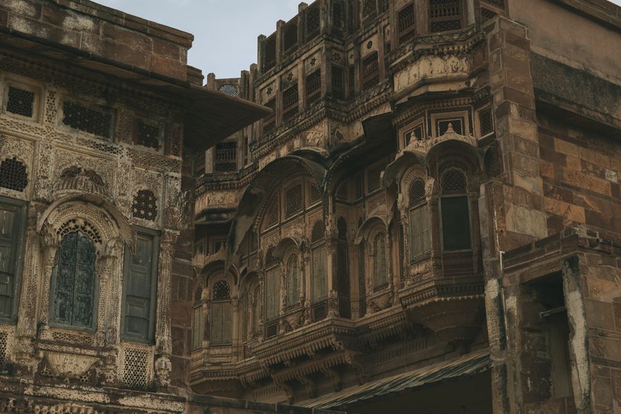 Ornate sandstone carvings and latticework adorn a historical building facade in Jodhpur, India.