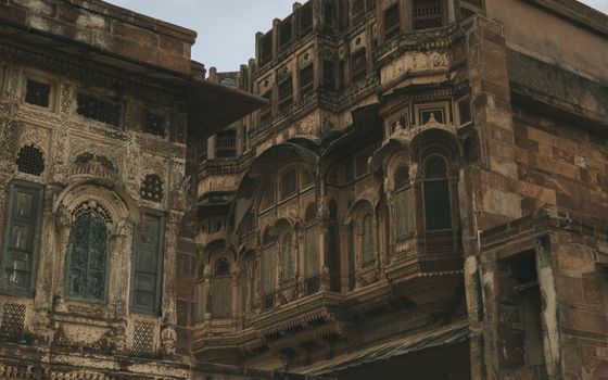 Ornate sandstone carvings and latticework adorn a historical building facade in Jodhpur, India.