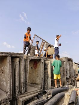 Group of children playing on large concrete blocks on a sunny day.