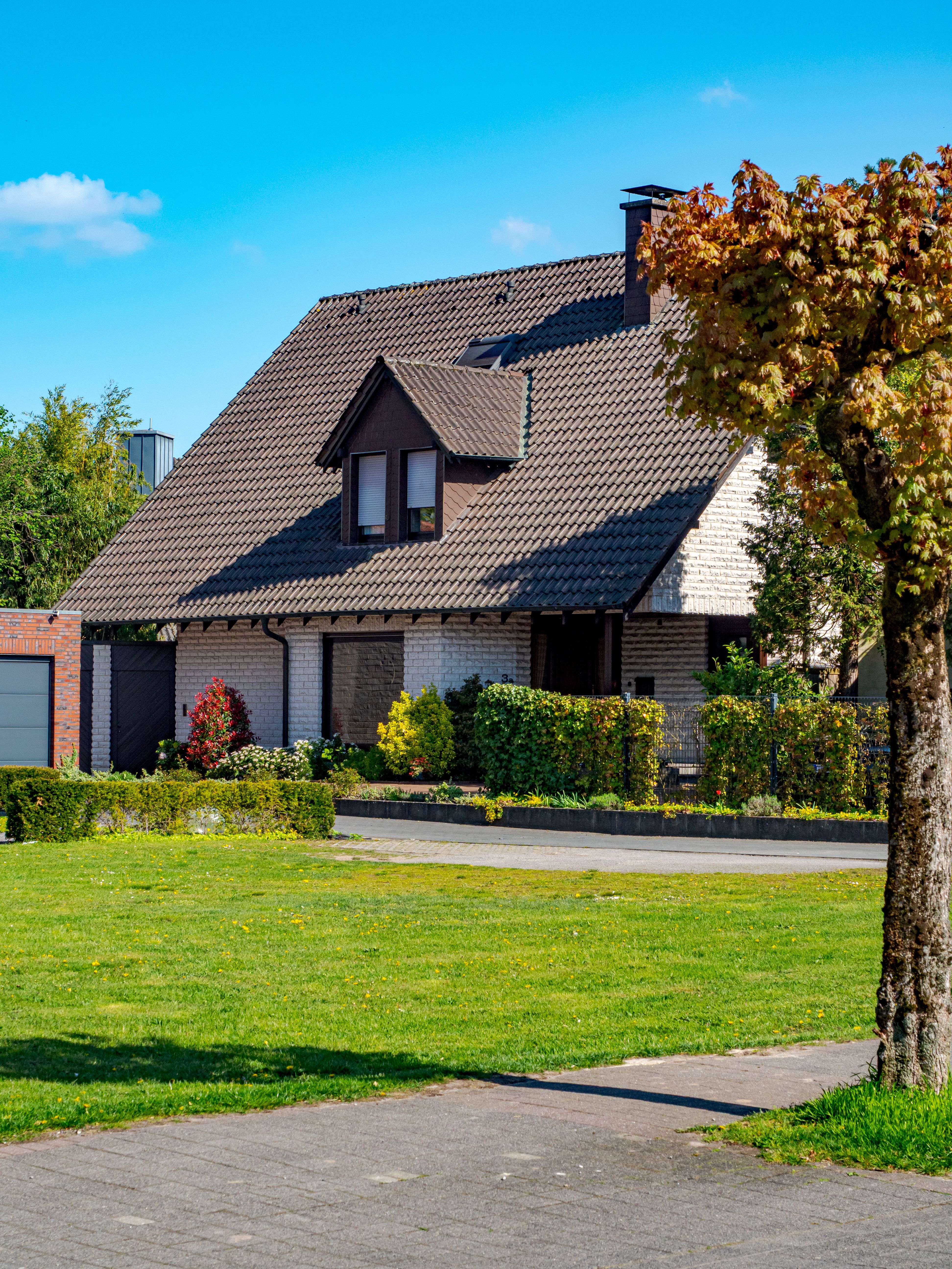 Alt Text: A beautiful, well-maintained single-family suburban home with a manicured green lawn, mature landscaping, and classic architectural details.