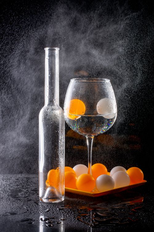 Free A creative still life featuring colored eggs in a glass with dramatic lighting. Stock Photo