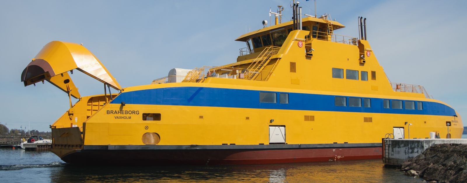 Bright yellow ferry docked at Visingsö in Sweden, showcasing marine transport.