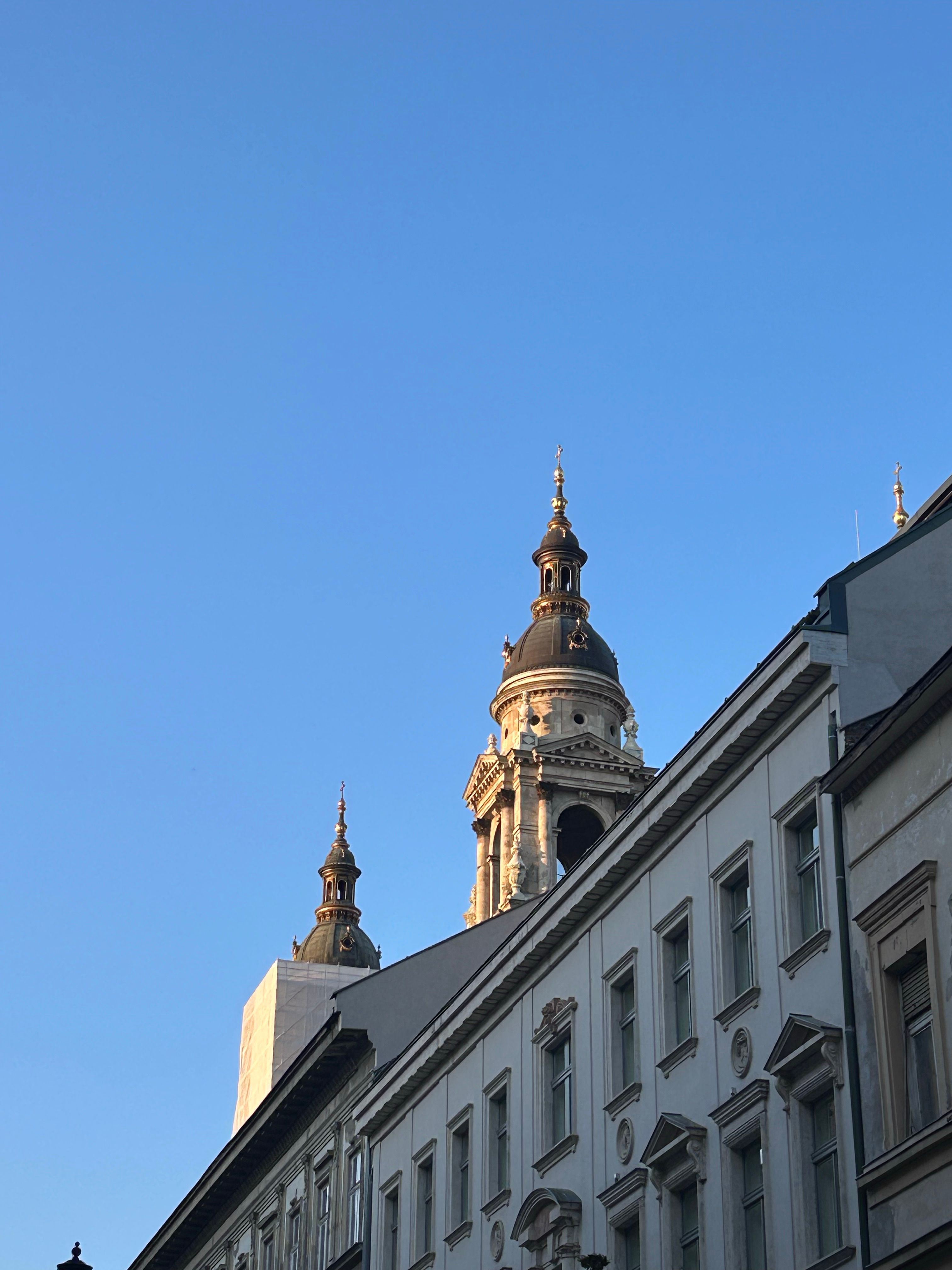 View of St. Stephen's Basilica towers in Budapest under a clear blue sky.