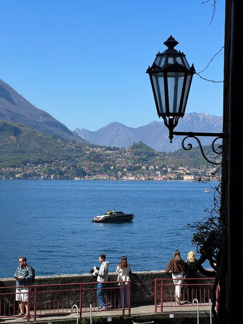 Free Vibrant Lake Como in Varenna, Italy, with mountains and people enjoying the view. Stock Photo