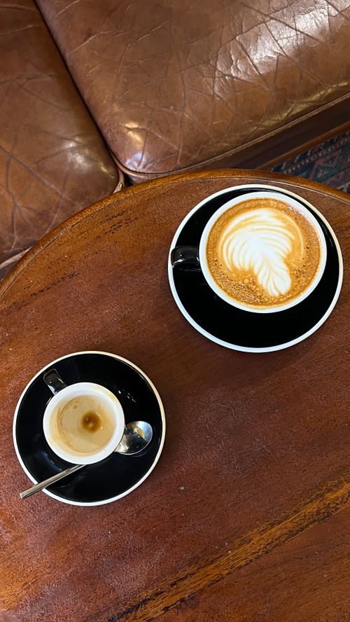 Free Top view of a cappuccino and espresso on a wooden table by a leather couch. Stock Photo