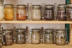 Glass jars filled with various spices and ingredients on wooden shelves promoting zero waste lifestyle.