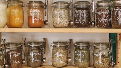 Glass jars filled with various spices and ingredients on wooden shelves promoting zero waste lifestyle.