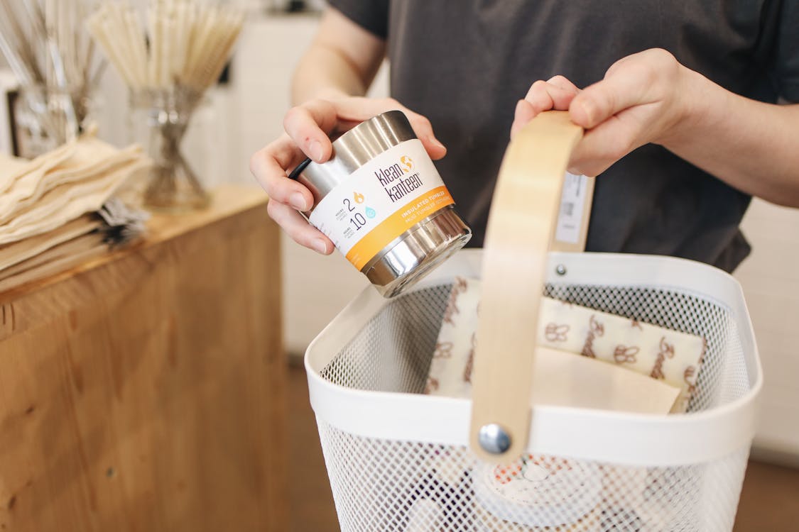 Person Placing Item into White Shopping Basket