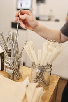 Person selecting metal straws in a zero waste shop with focus on sustainability.