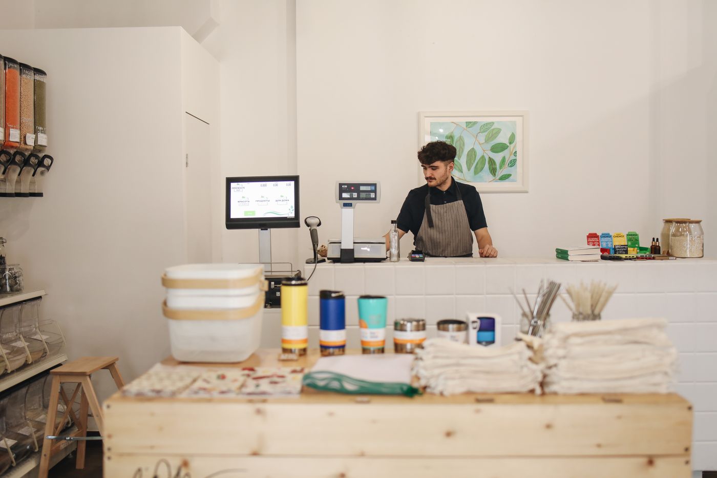 Foto real: caixa da loja atendendo cliente com produtos no balcão