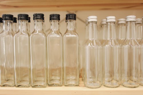 Gratis Bottiglie Di Vetro Trasparenti Sul Ripiano In Legno Marrone Foto a disposizione