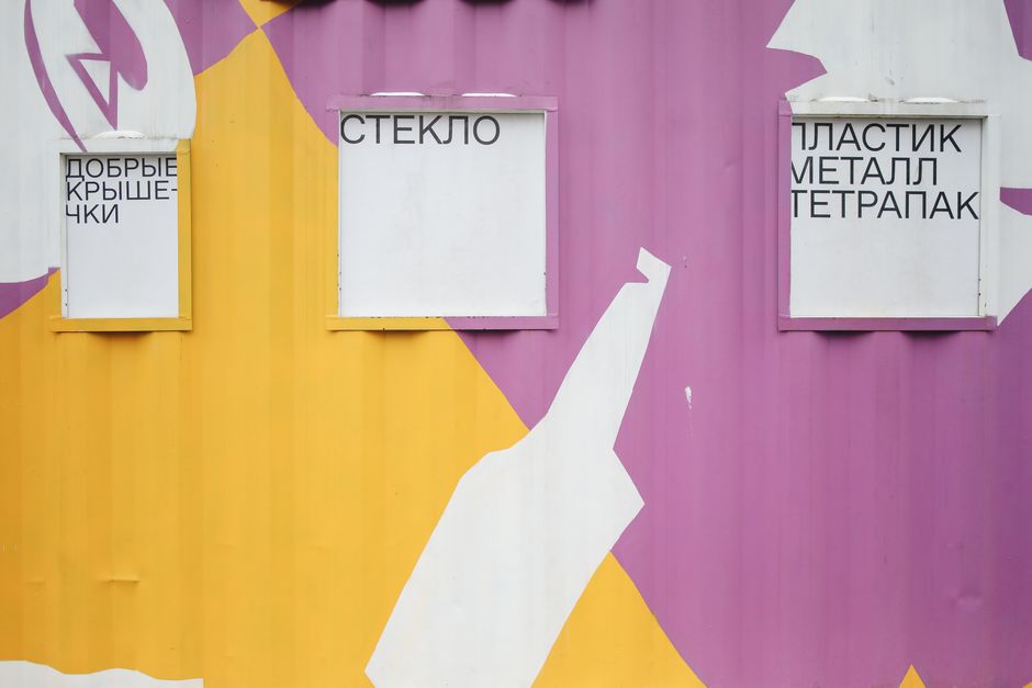 Bright recycling bins for glass, plastic, metal, and tetra pak segregation on a painted wall.