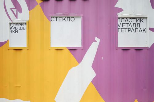 Free Bright recycling bins for glass, plastic, metal, and tetra pak segregation on a painted wall. Stock Photo