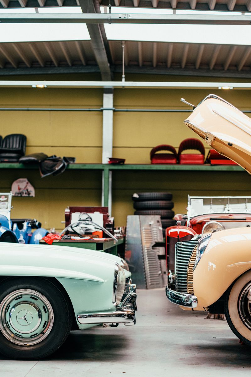 Explore classic cars inside a vintage auto workshop with retro interiors and open hoods.