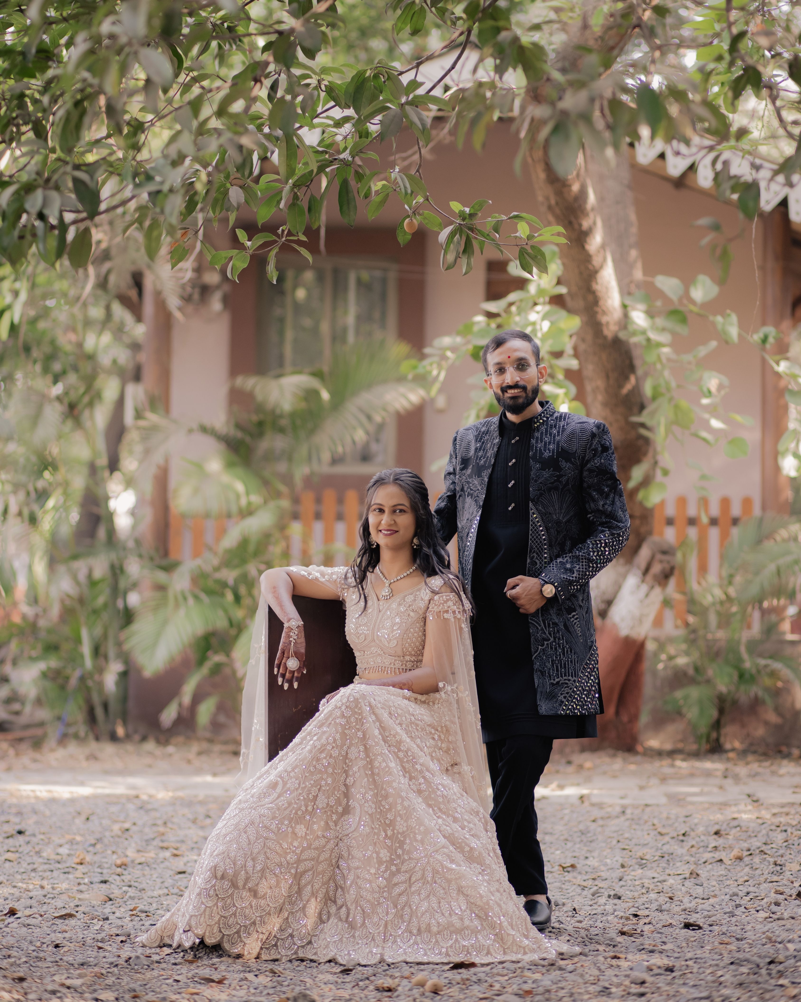 Couple dressed in formal attire posing elegantly in a picturesque garden setting.