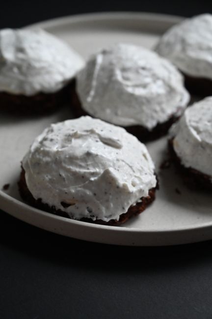 A butter knife spreading glossy white icing over a star-shaped sugar cookie on a cooling rack, with a bowl of extra icing and a small dish of sprinkles beside it.