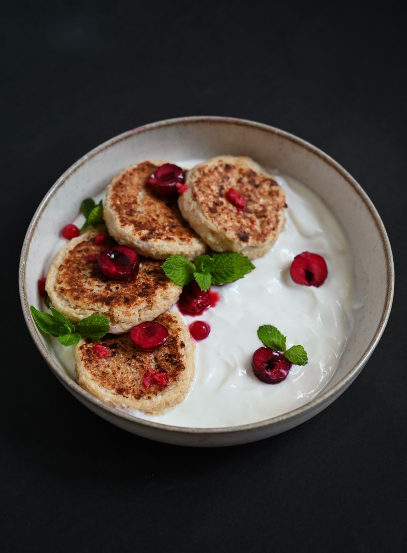 Golden oat mini pancakes on coconut yogurt with cherries and mint