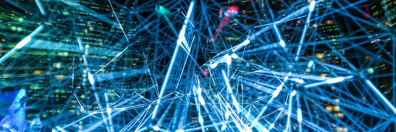 Dynamic urban scene showcasing interconnected light trails representing digital communication networks.